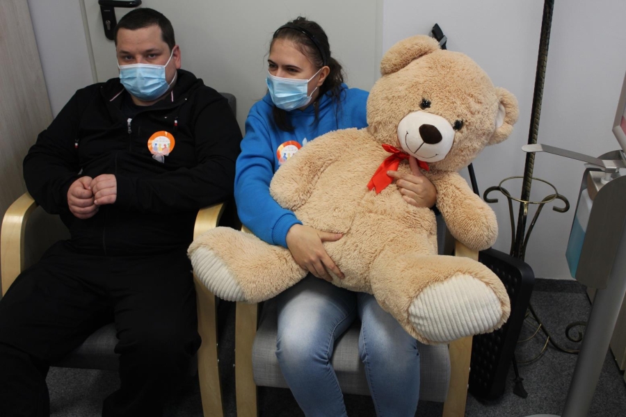 Uczestniczka trzymająca dużego pluszowego misia w towarzystwie Uczestnika.