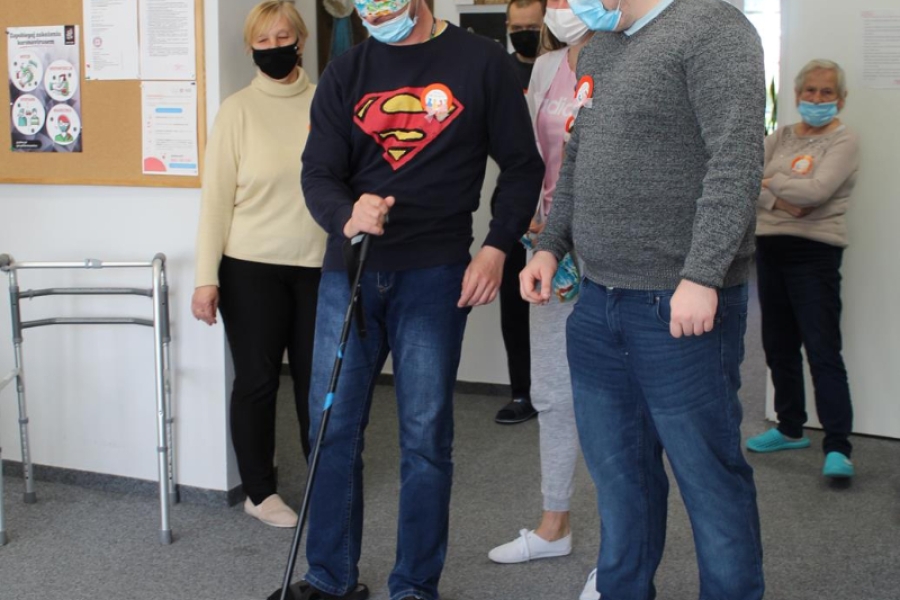 Uczestnik w asyście terapeuty pokonujący tor przeszkód z zasłoniętymi oczami.