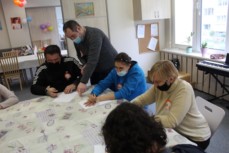 Uczestnicy w asyście Terapeuty odrysowujący dłonie na kartce. 