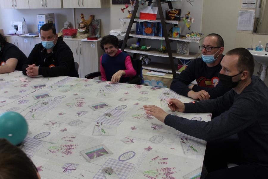 Uczestnicy podczas zabawy z piłką przy stole.