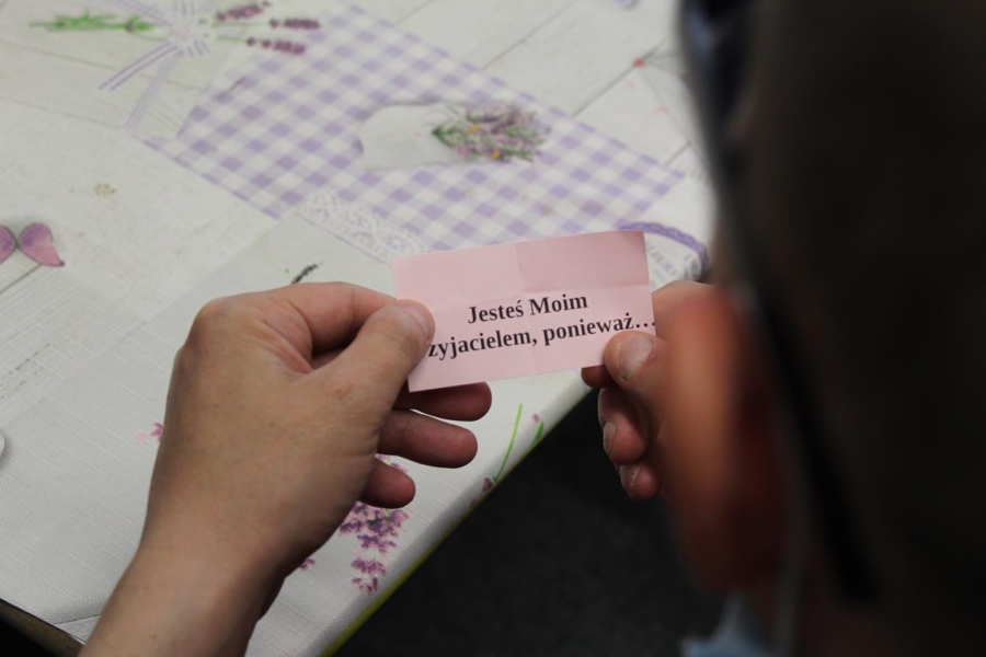 Uczestniczka trzymająca kartkę z napisem „Jesteś Moim przyjacielem, ponieważ...”.