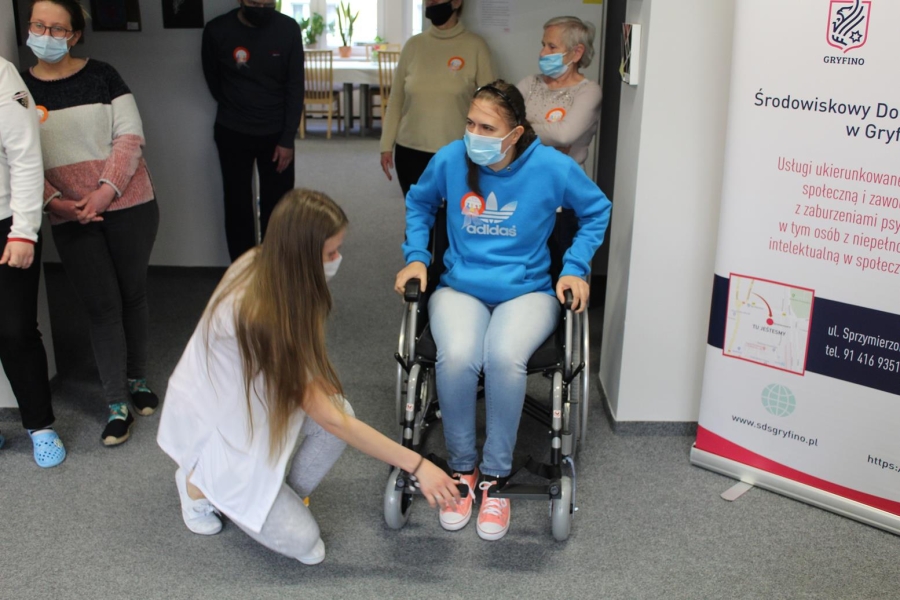 Uczestniczka przygotowująca się do slalomu na wózku inwalidzkim z piłką na kolanach.