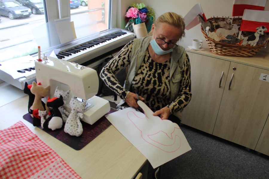 3 Uczestniczka siedzi przy maszynie do szycia i wycina szablony kotów w papierze.