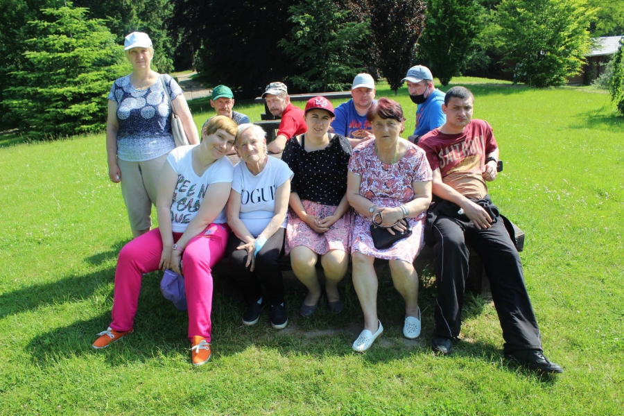 3 Uczestnicy siedzący na ławce wśród zieleni. 