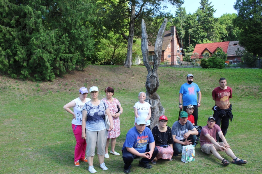 4 Grupa Uczestników na tle drewnianej rzeźby orła.