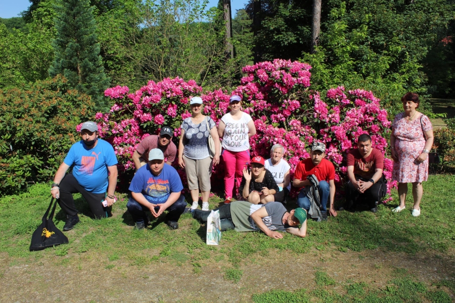 5 Grupa Uczestników na tle różowych kwiatów. 