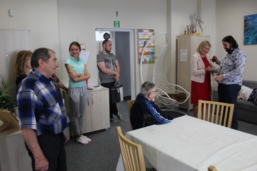 11. Kierownik ŚDS w Gryfinie wręczająca róże Uczestnikowi na tle grupy.