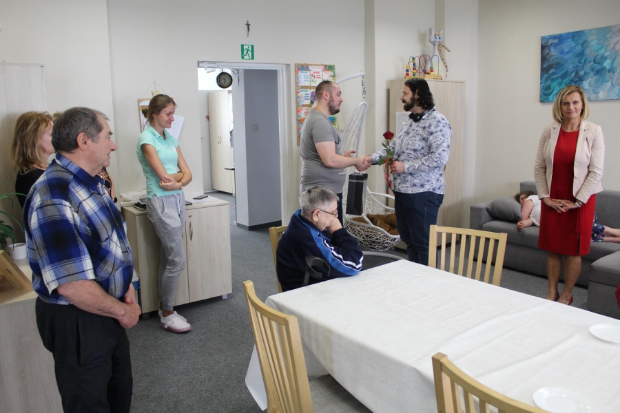 12. Terapeuta gratulujący Uczestnikowi na tle grupy.