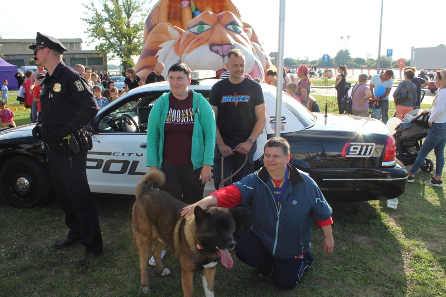 9 -  Uczestniczki ŚDS w Gryfinie pozują do zdjęcia z psem na tle radiowozu.