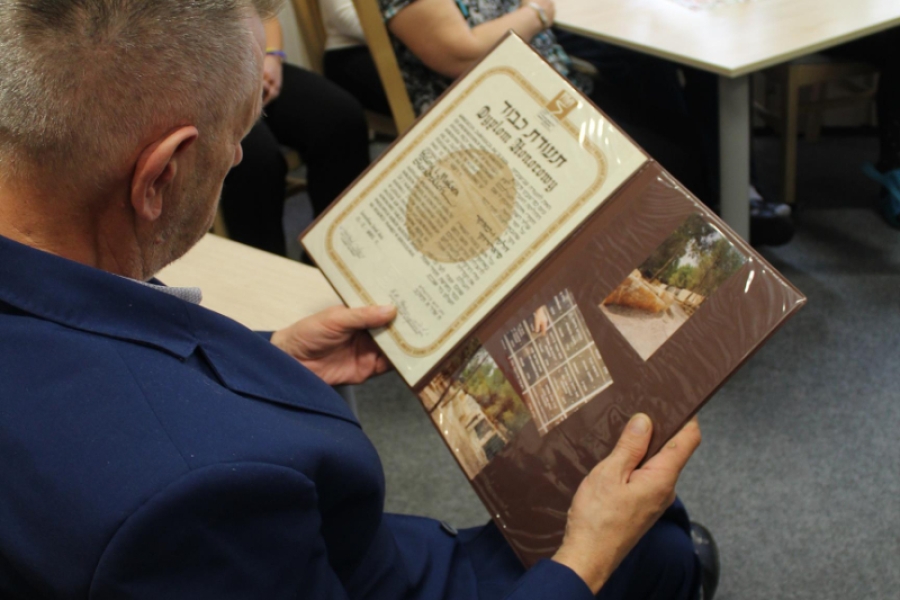 8 - Uczestnik trzymający w dłoniach odznaczenie Sprawiedliwy wśród Narodów Świata.