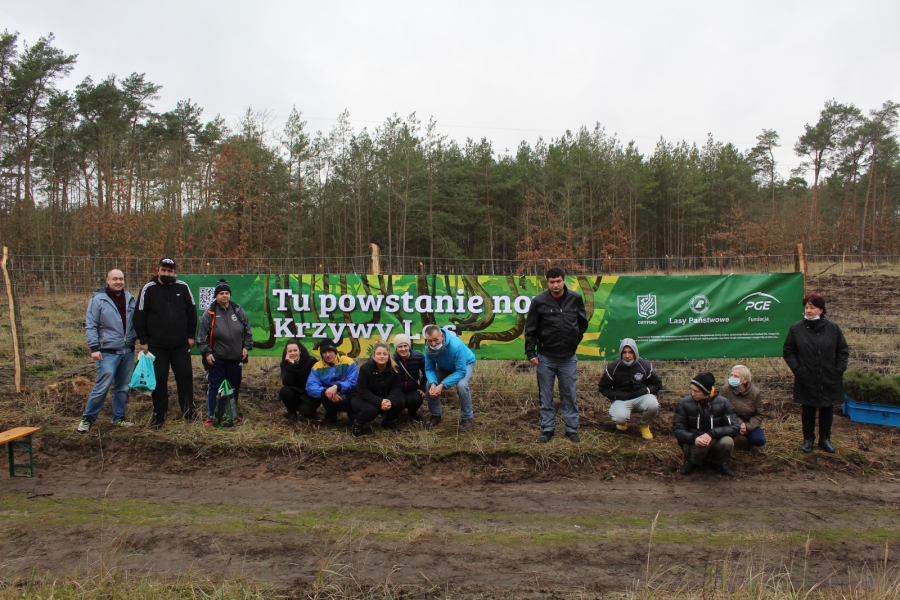 2 -  Grupa Uczestników wraz z terapeutami pozują do zdjęcia na tle banera. 